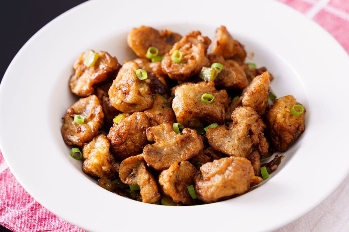 closeup shot of of chilli mushroom in a shallow white bowl