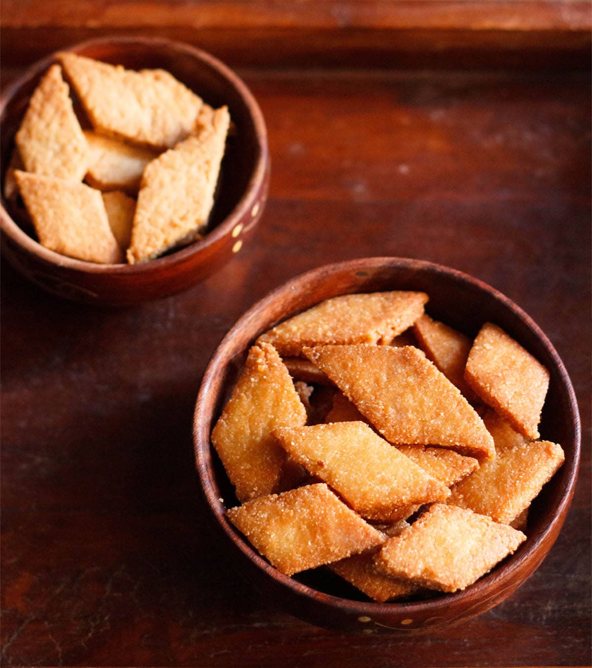 shankarpali, fried and baked version in two wooden bowls on a mahogany wooden board