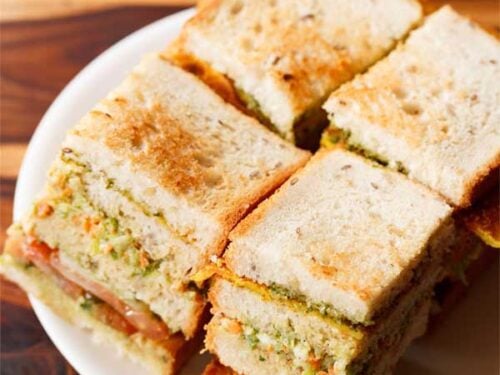 club sandwich squares with layers seen on a white plate.