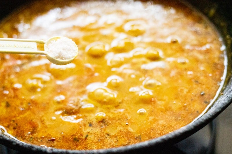 salt being added from a white measuring spoon to chana dal