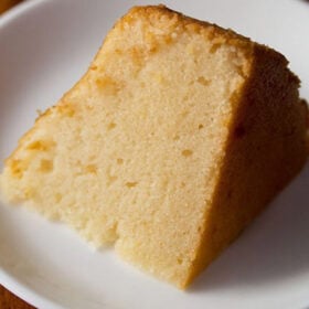 closeup photo of thick slice of pressure cooker cake on white plate