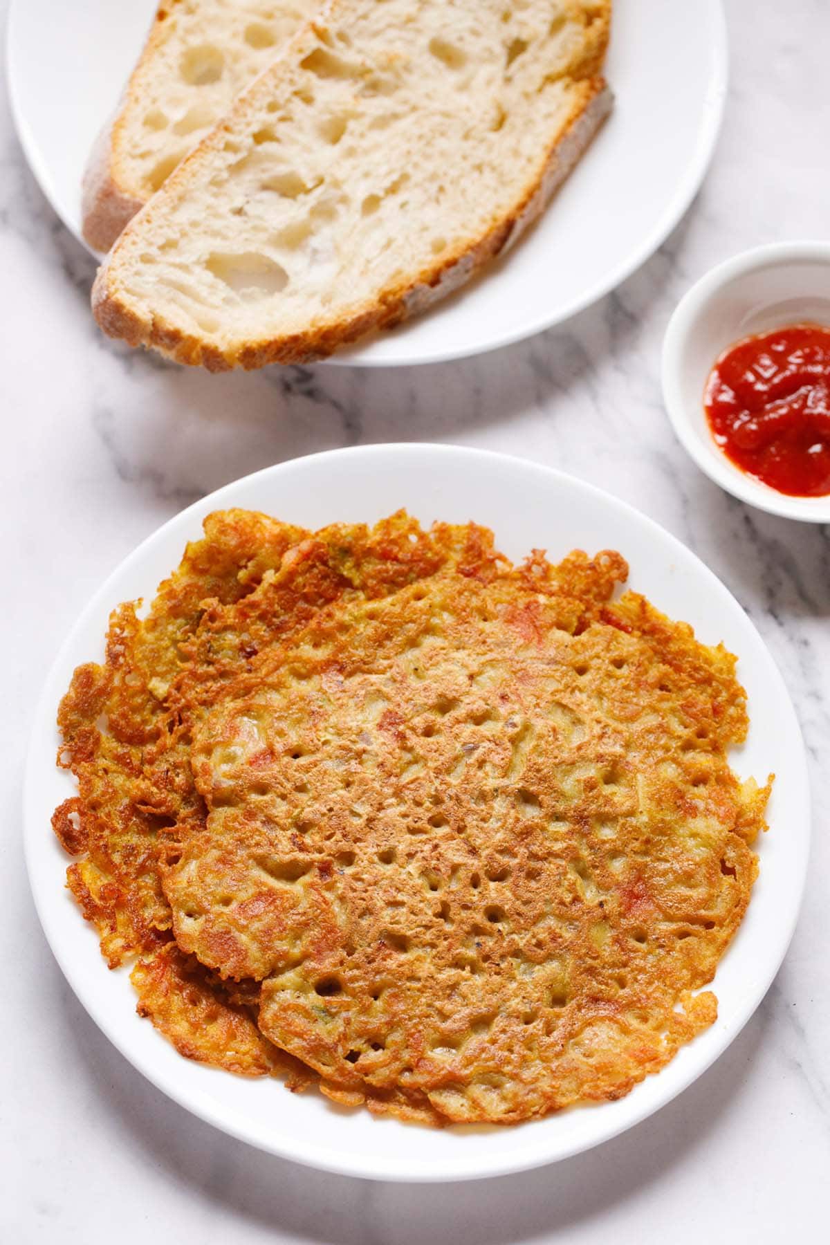 eggless omelette on white plate with a side plate of crusty baguette and a side bowl of tomato ketchup