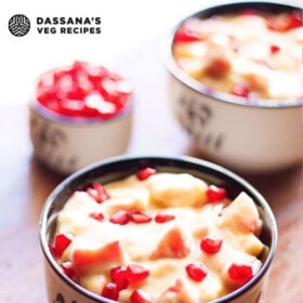 closeup shot of two black and white bowls filled with fruit custard and garnished with pomegranate arils with text layovers