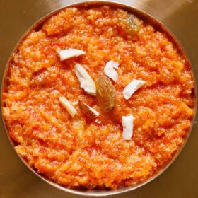 overhead shot of gajar halwa or carrot halwa filled in a bronze bowl placed on a bronze plate