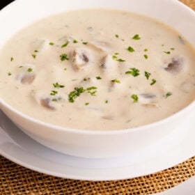 closeup shot of cream of mushroom soup in a white bowl placed on burlap.