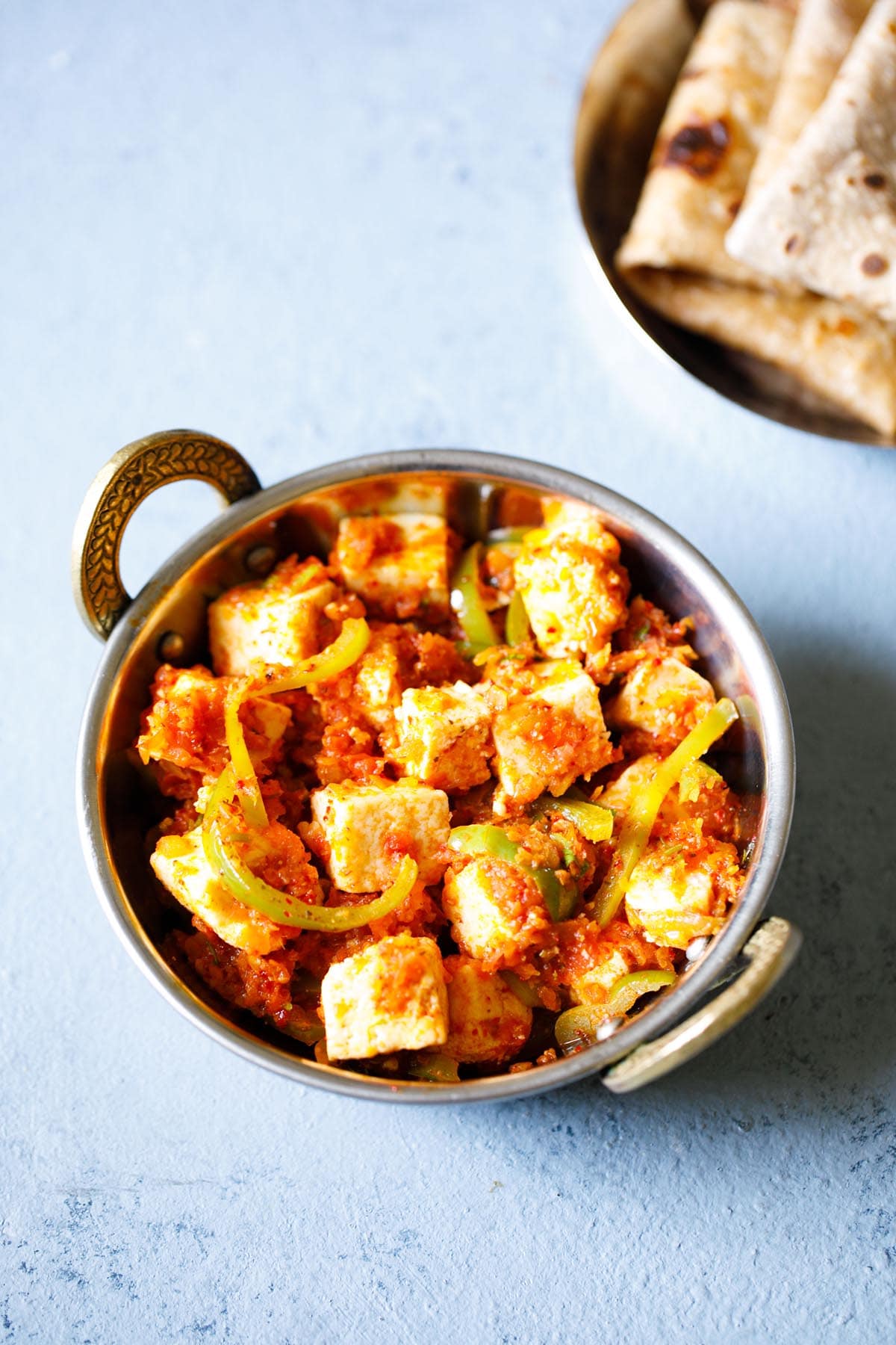 kadai paneer in a small kadai (Indian wok) on a light blue board