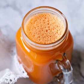 carrot juice in a glass jar with a white doily by the side