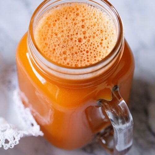 carrot juice in a glass jar with a white doily by the side