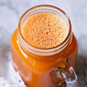 carrot juice in a glass jar with a white doily by the side with text layovers