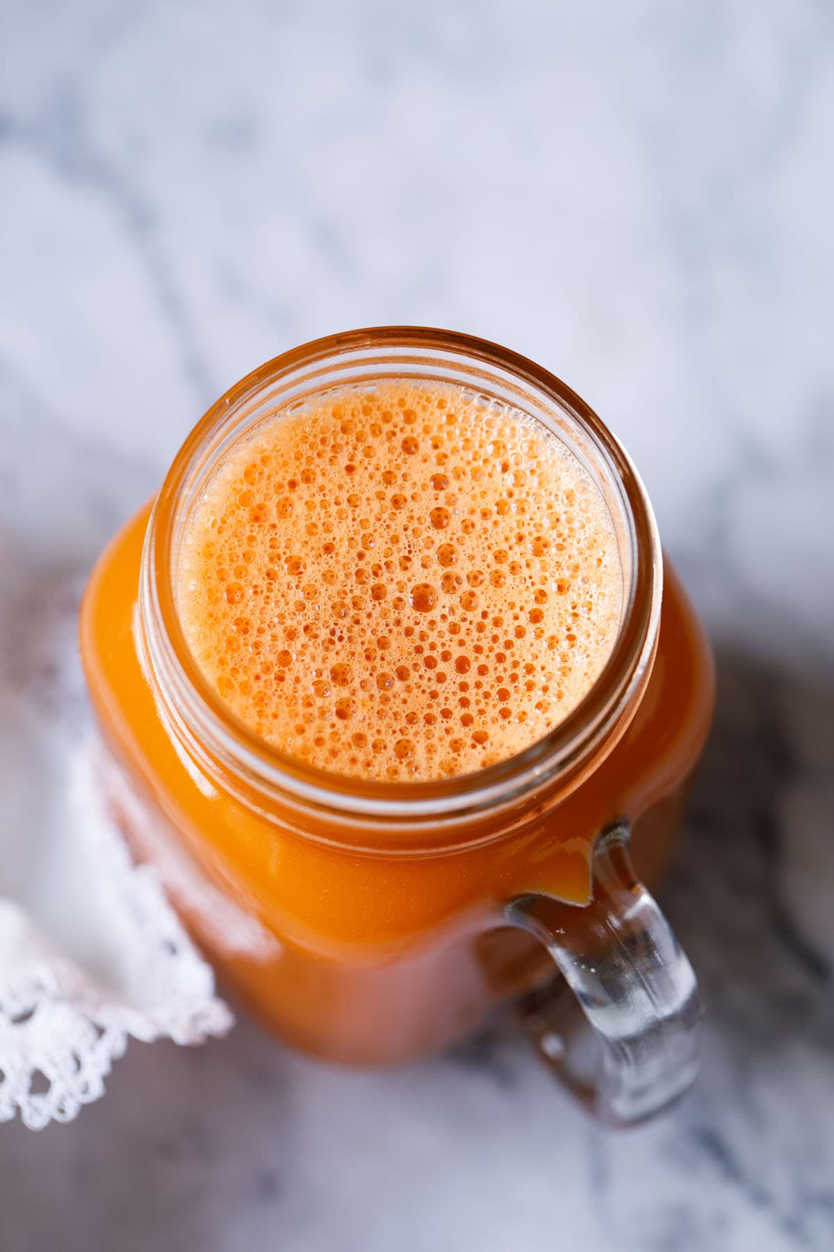 carrot juice in a glass jar with a white doily by the side