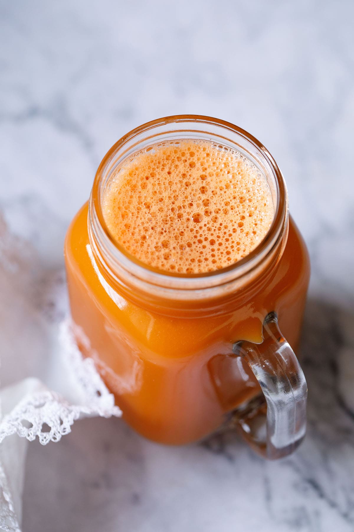 carrot juice in a glass jar with a white doily by the side