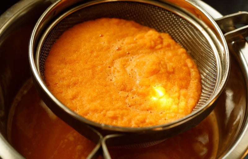 straining the blender carrot juice to remove pulp.