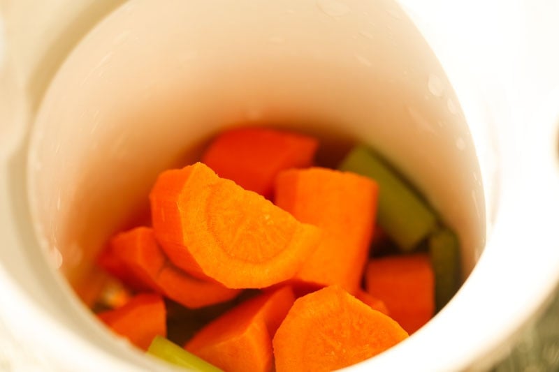 carrots and celery added to chute of a juicer.