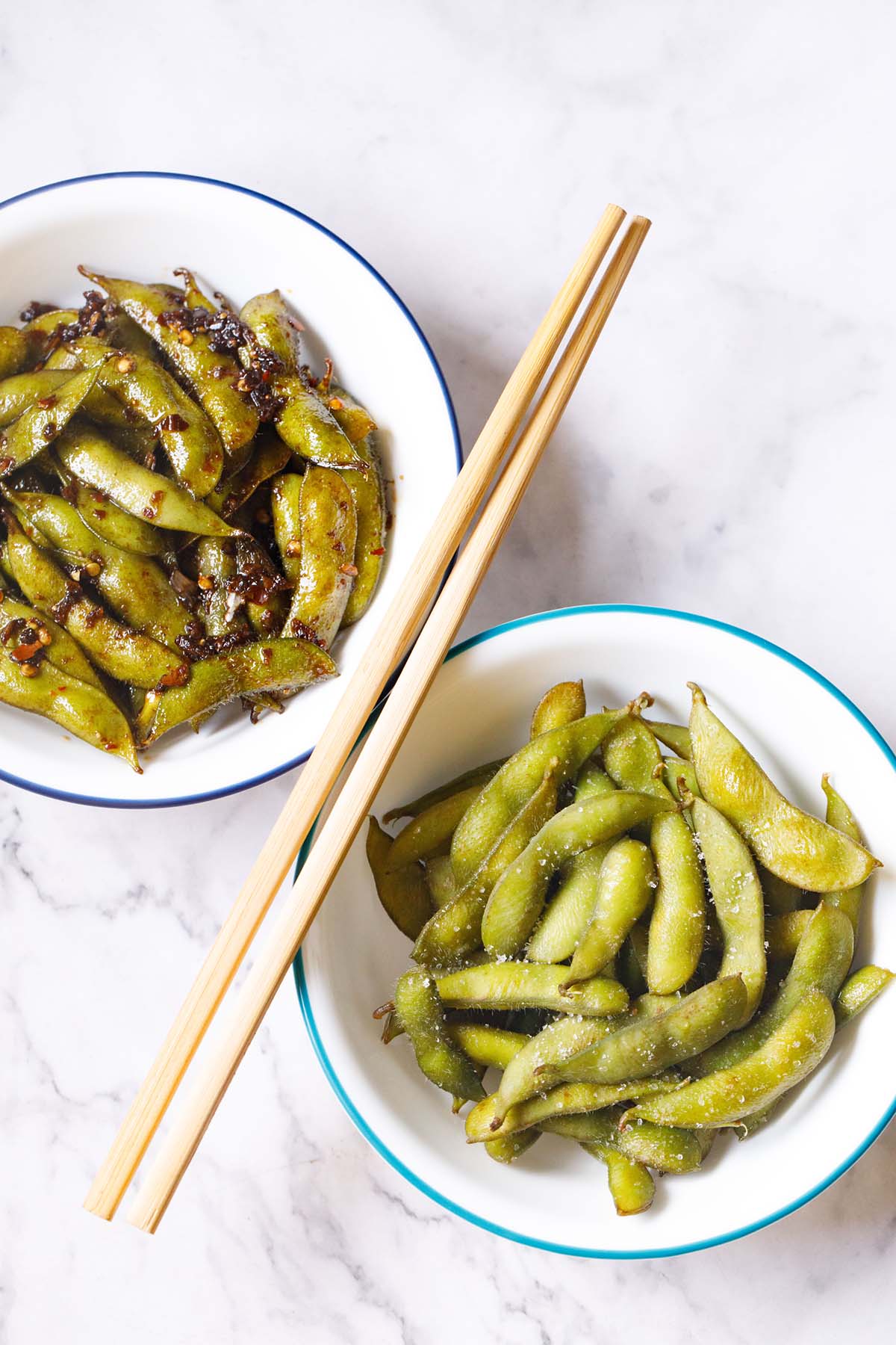 two unique edamame recipes served in two white bowls with chopsticks in the center.
