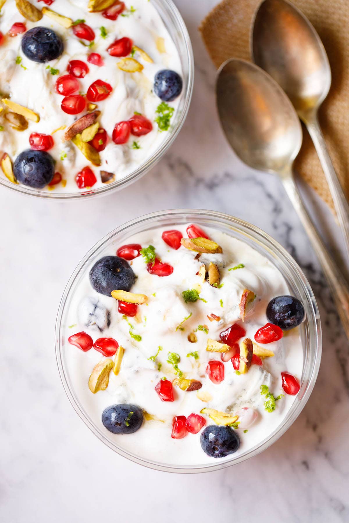 fruit cream in glass bowls with dessert spoons by the side