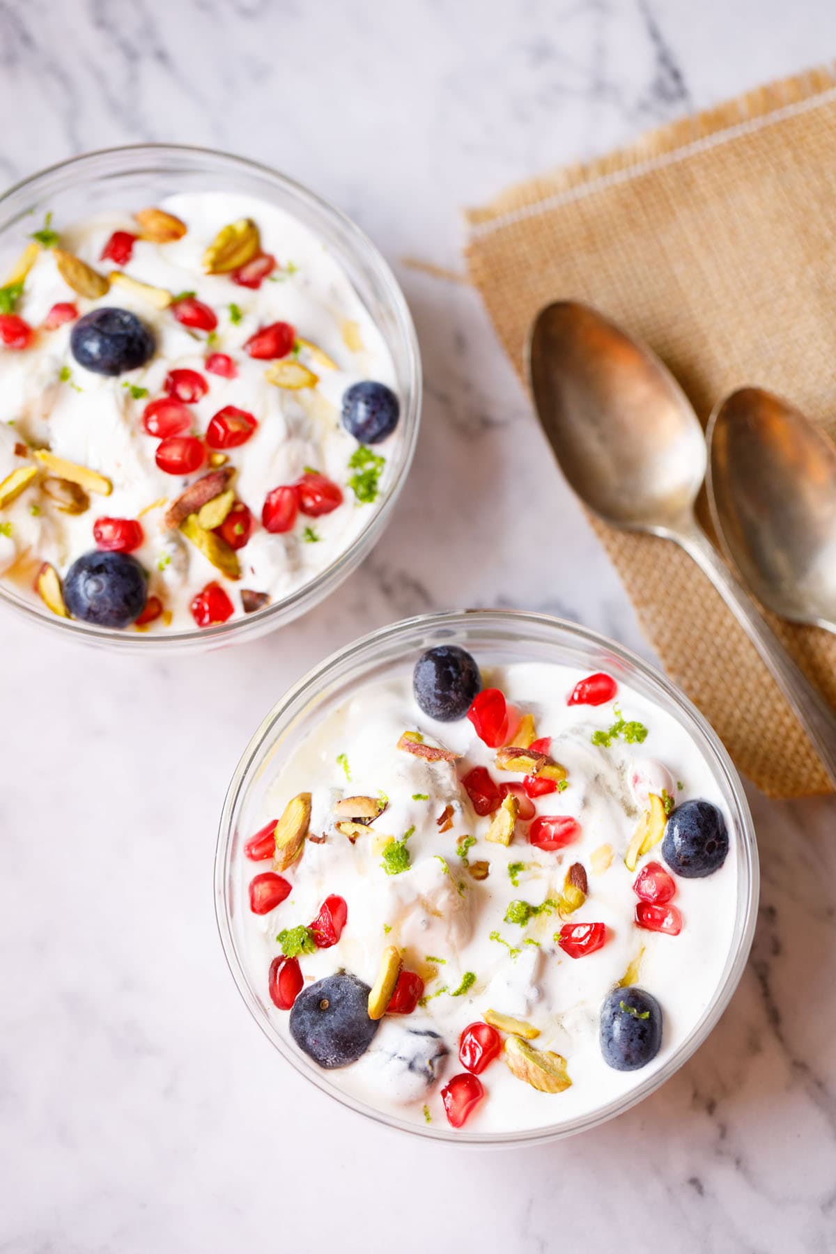 fruit cream in glass bowls with dessert spoons placed on burlap