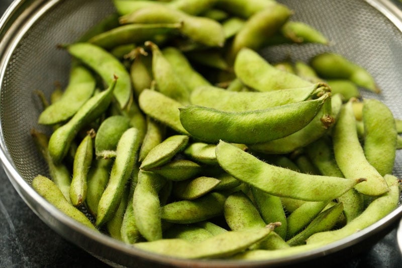 fresh edamame pods in a mesh strainer.