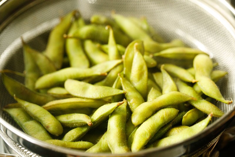 drained, cooked edamame bean pods in a mesh strainer.