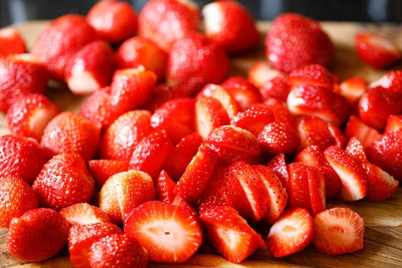 sliced strawberries on a cutting board.
