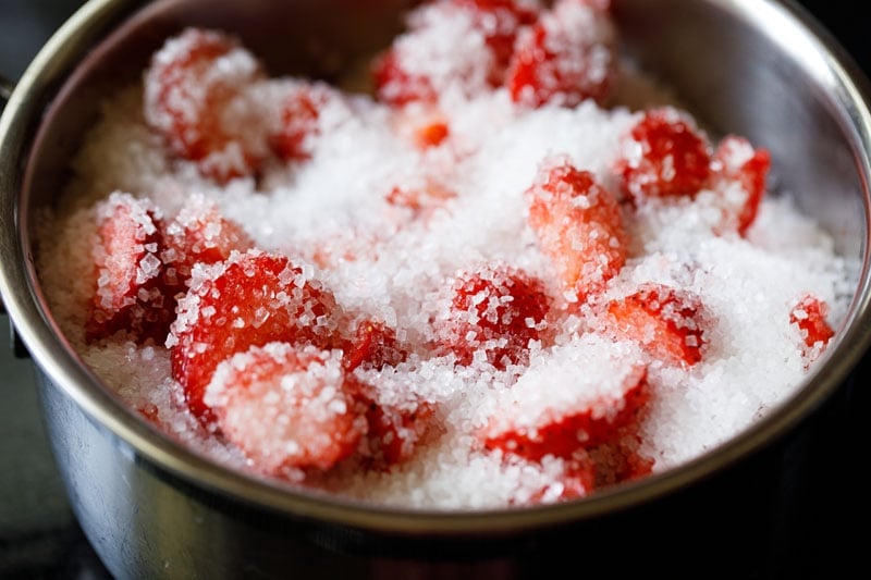 strawberries and sugar added to a saucepan.