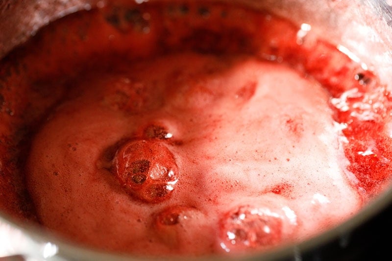 rosafarbener Schaum in der Mitte der Pfanne zeigt an, dass die Erdbeermarmelade fertig ist.