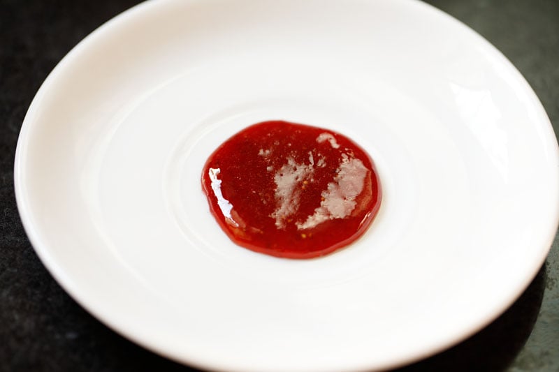 testing the jam for doneness on a white plate - it is set and there is no separation of liquid.