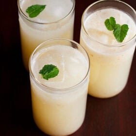 Litchi juice in three glasses garnished with mint sprig.