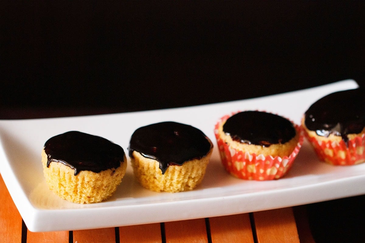 orange muffins with chocolate glaze on top on white tray