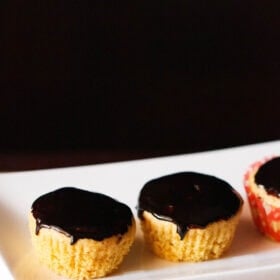 orange muffins with chocolate glaze on top on white tray