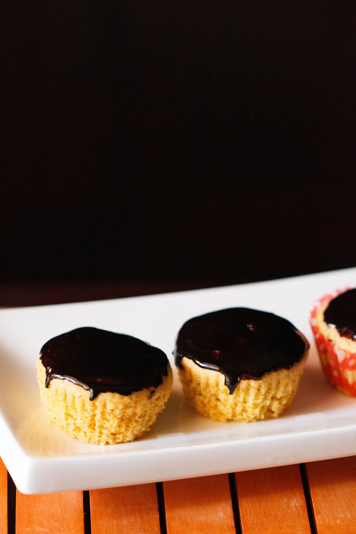 orange muffins with chocolate glaze on top on white tray