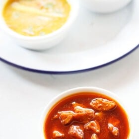 amla pickle served in a white bowl with an Indian meal on a white board.