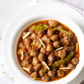 amritsari chole garnished with ginger juliennes and served in a white bowl.