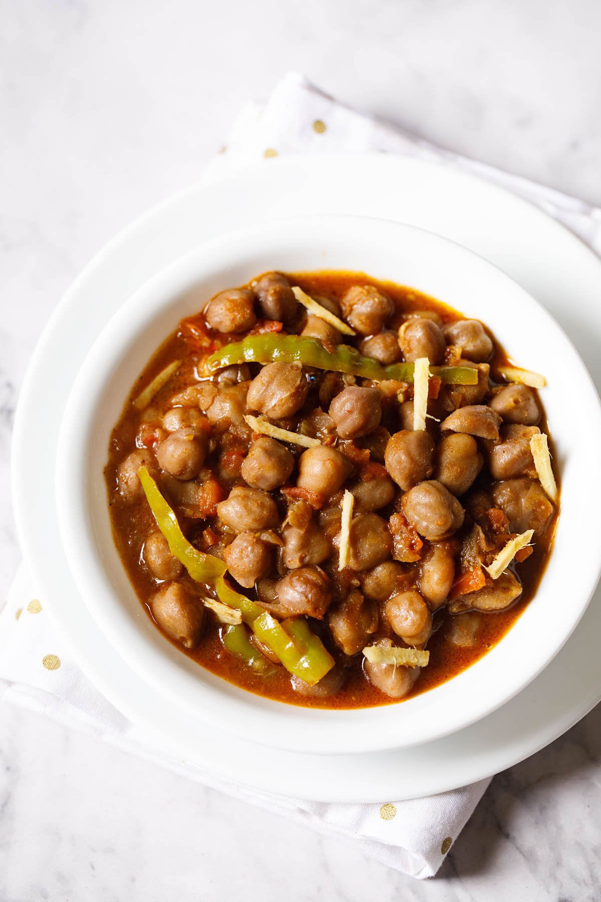 amritsari chole garnished with ginger juliennes and served in a white bowl. 