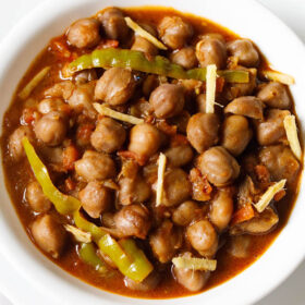 amritsari chole garnished with ginger juliennes and served in a white bowl.