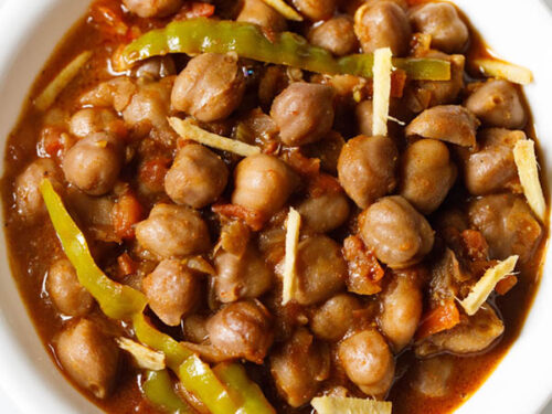amritsari chole garnished with ginger juliennes and served in a white bowl.
