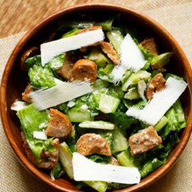 caesar salad with parmesan shavings in a wooden bowl.