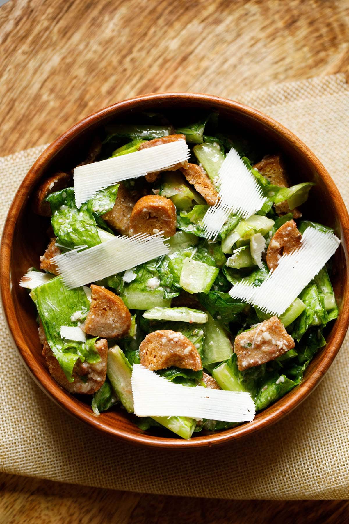 caesar salad with parmesan shavings in a wooden bowl.