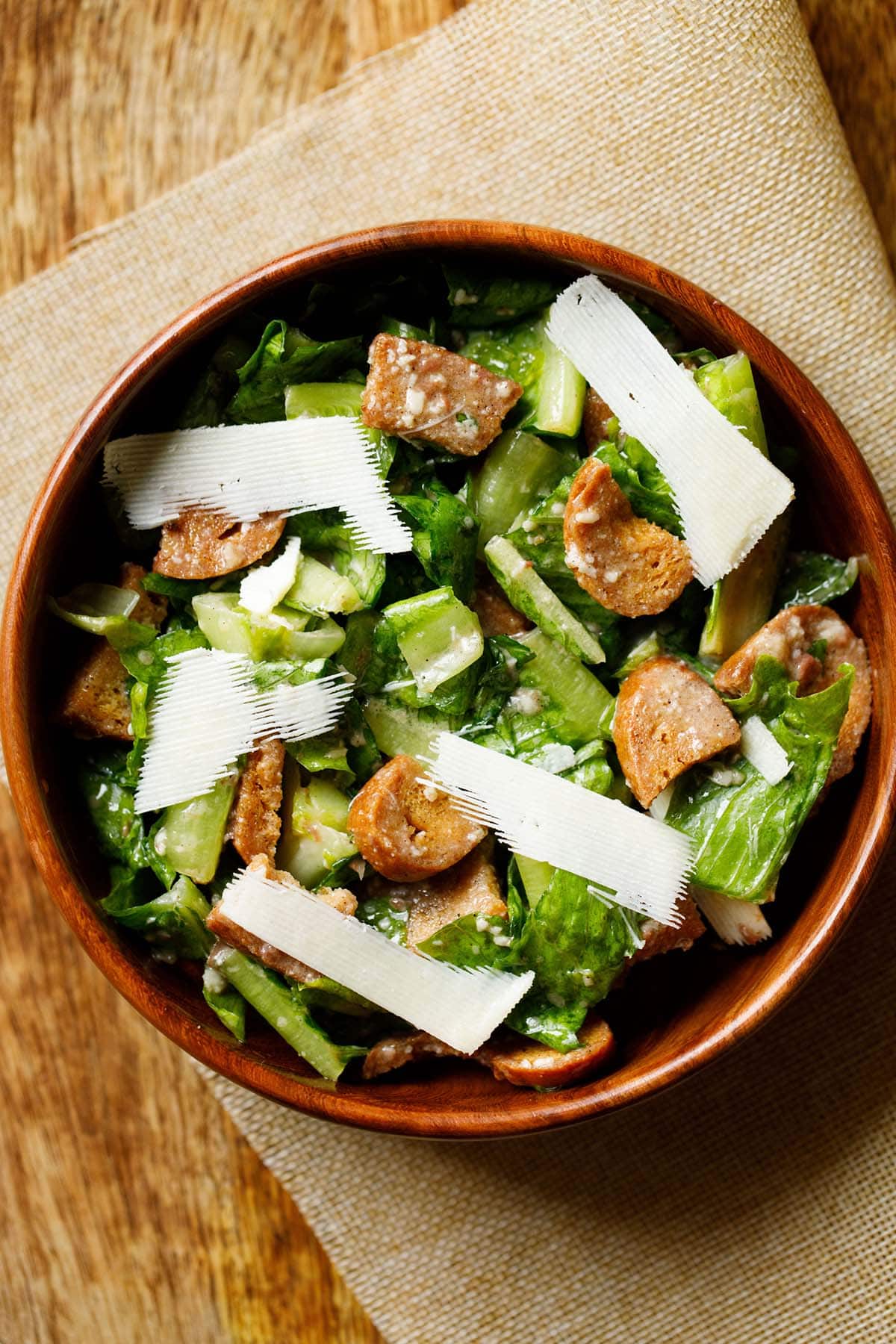 caesar salad with parmesan shavings in a wooden bowl.