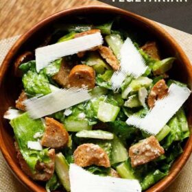 top shot of caesar salad with parmesan shavings in a wooden bowl with text layovers.