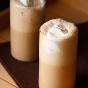 2 coffee milkshakes with ice cream on a beige table