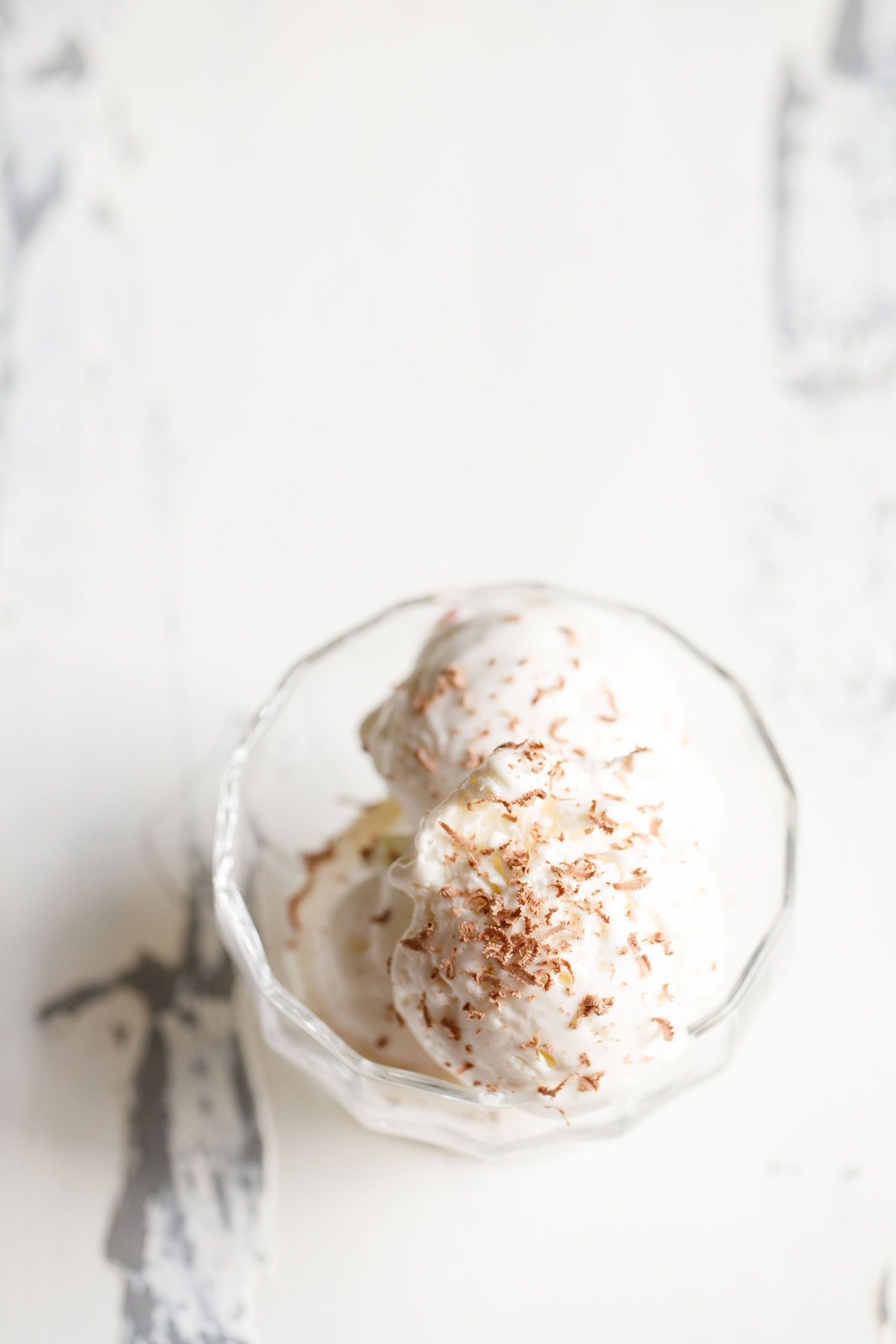 ice cream scoops in a glass bowl topped with grated chocolate.