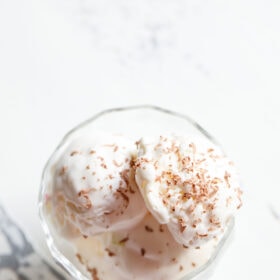 ice cream scoops in a glass bowl topped with grated chocolate.