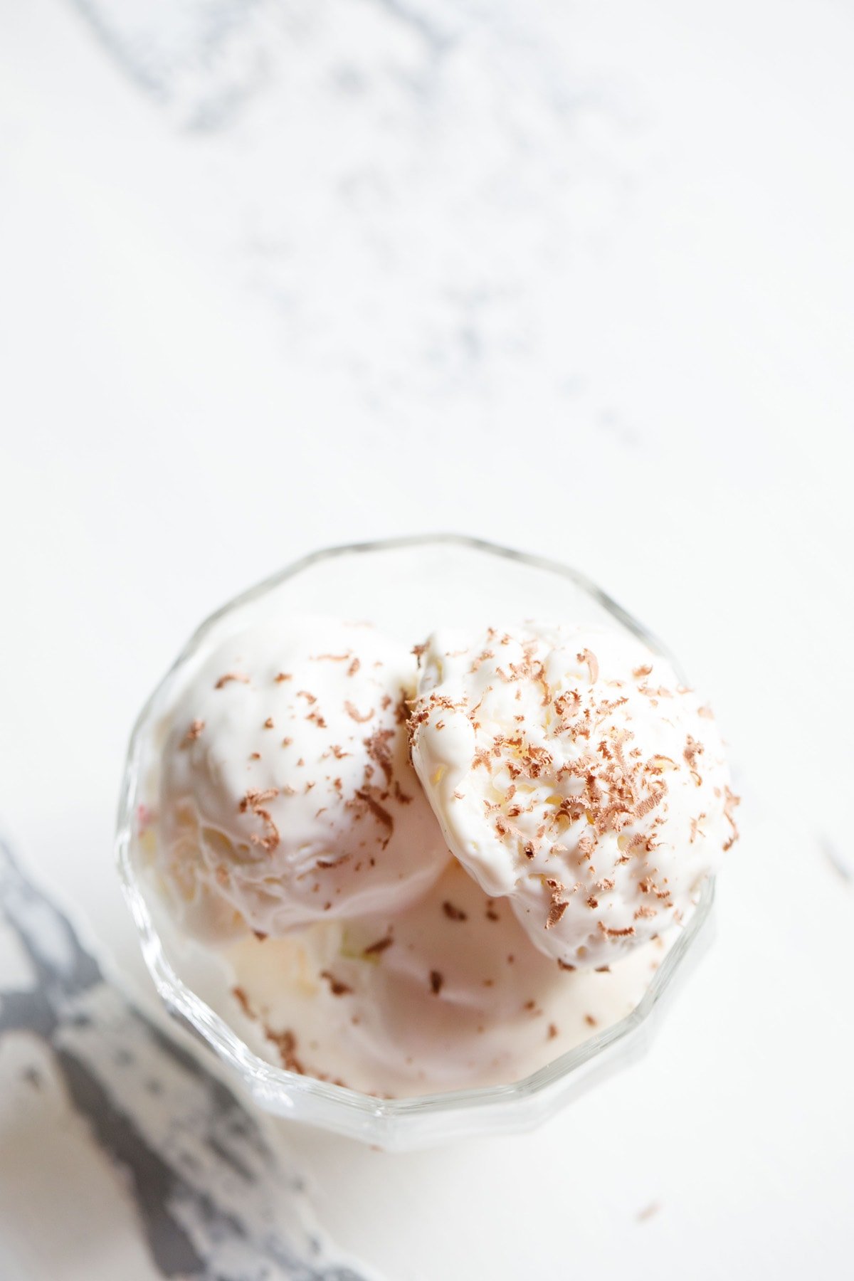 ice cream scoops in a glass bowl topped with grated chocolate.