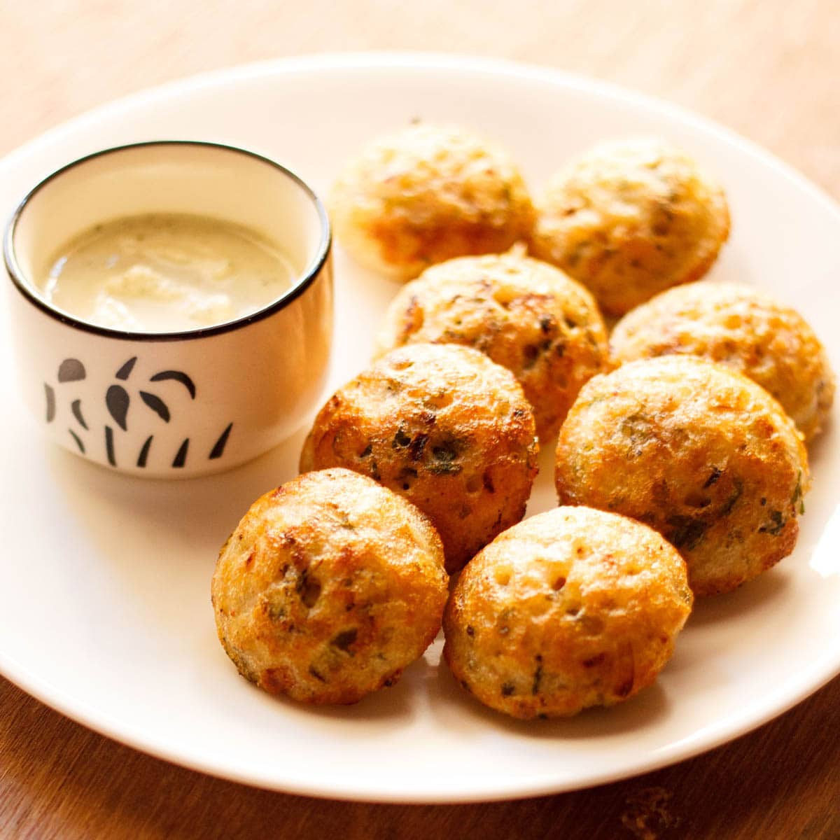 paniyaram on a plate with a side of coconut chutney.