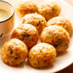 paniyaram on a plate with a side of coconut chutney.