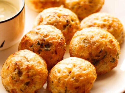 paniyaram on a plate with a side of coconut chutney.