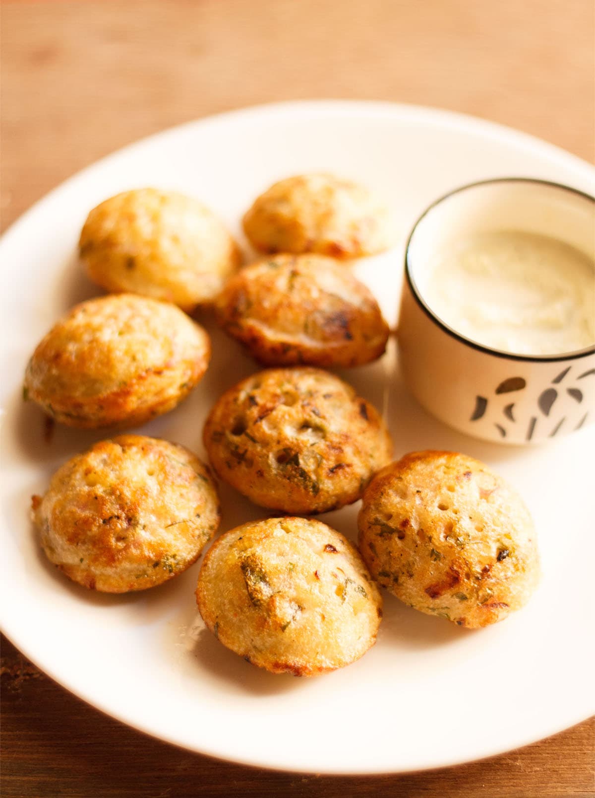 paniyaram on a plate with a side of coconut chutney.