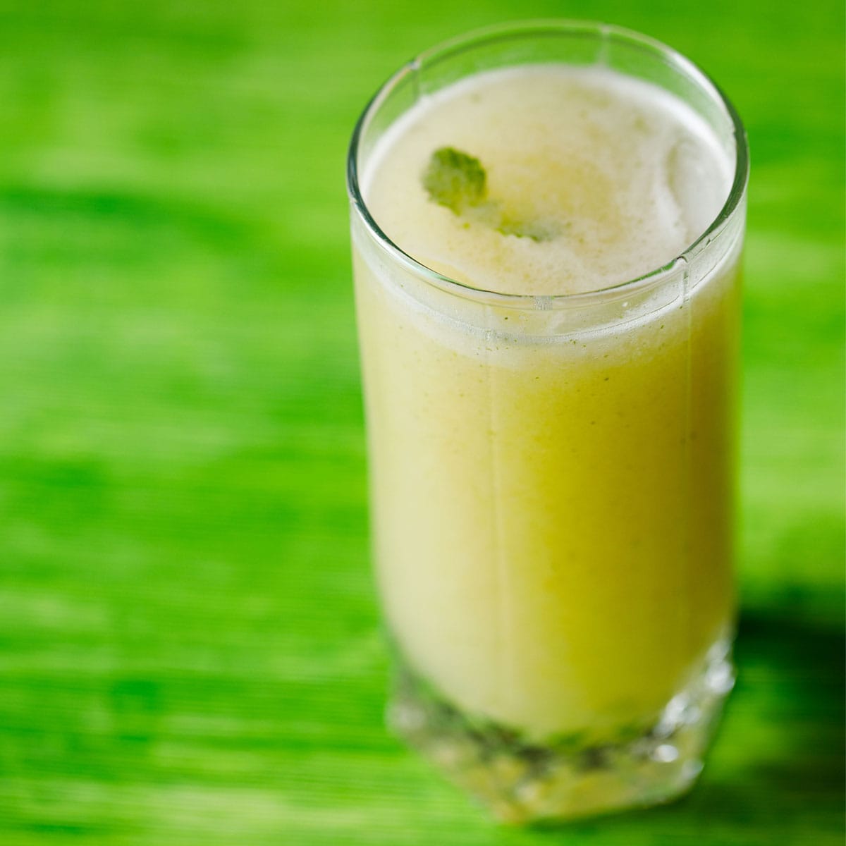 roasted aam panna in a glass on a green table.