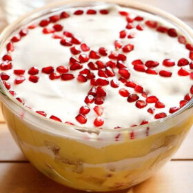top shot of trifle with top cream layer garnished with wheel like design with pomegranate seeds.