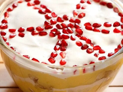 top shot of trifle with top cream layer garnished with wheel like design with pomegranate seeds.
